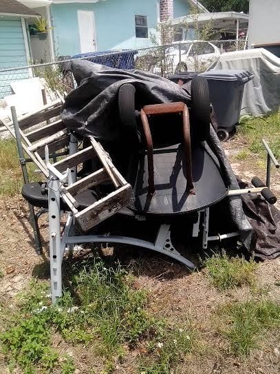 A pile of trash is sitting in the grass in front of a house.